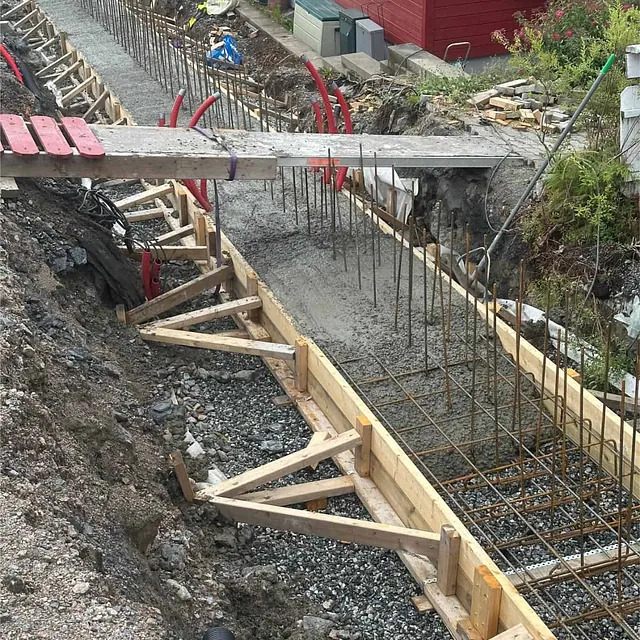 Forskalet og armert fundament for støttemur under pågående betongarbeider på tomten.