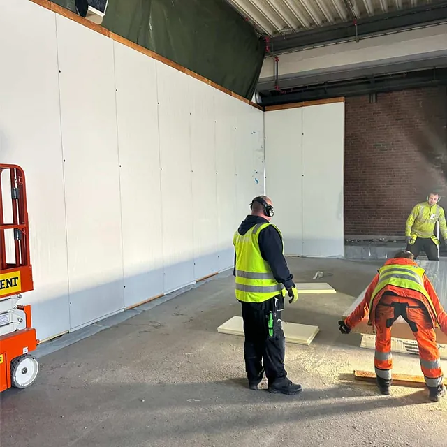 Arbeidere monterer isolasjon på eksisterende betonggulv som del av oppbygging av nytt dekke.