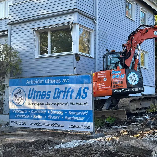 Gravemaskin benyttes ved bolig under omfattende bergarbeid og terrengtilpasning på tomten.