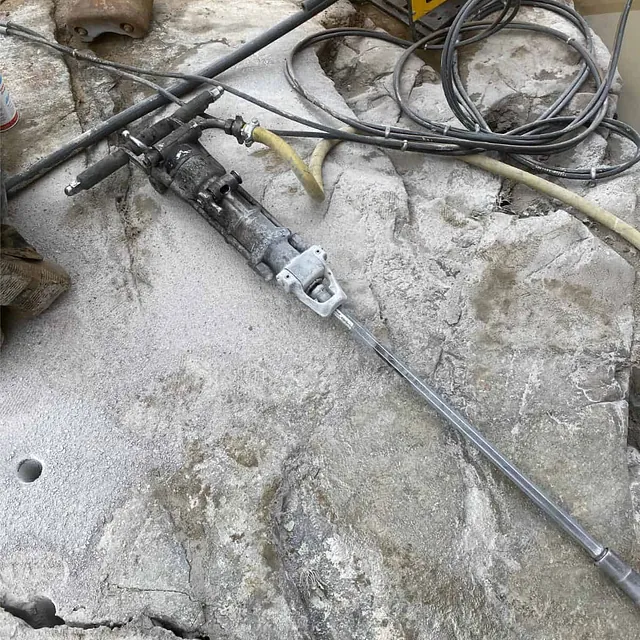 Hydraulisk kileutstyr montert i borehull for kontrollert splitting og fjerning av berg.
