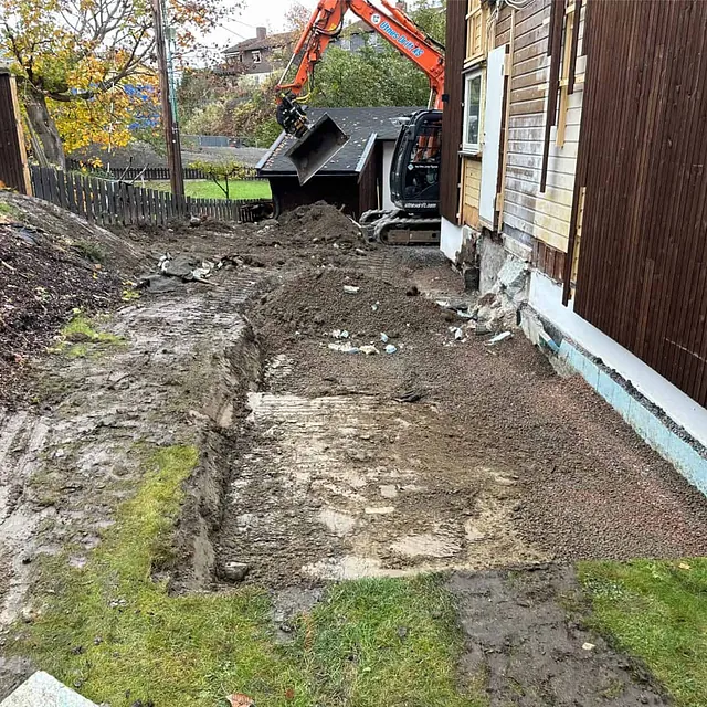 Utgraving og planering langs bolig før etablering av nytt tilbygg og fundamentarbeider.