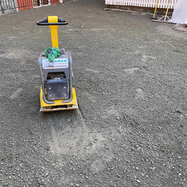 Komprimering av bærelag med vibroplate før asfaltering av gårdsplass og gangarealer.