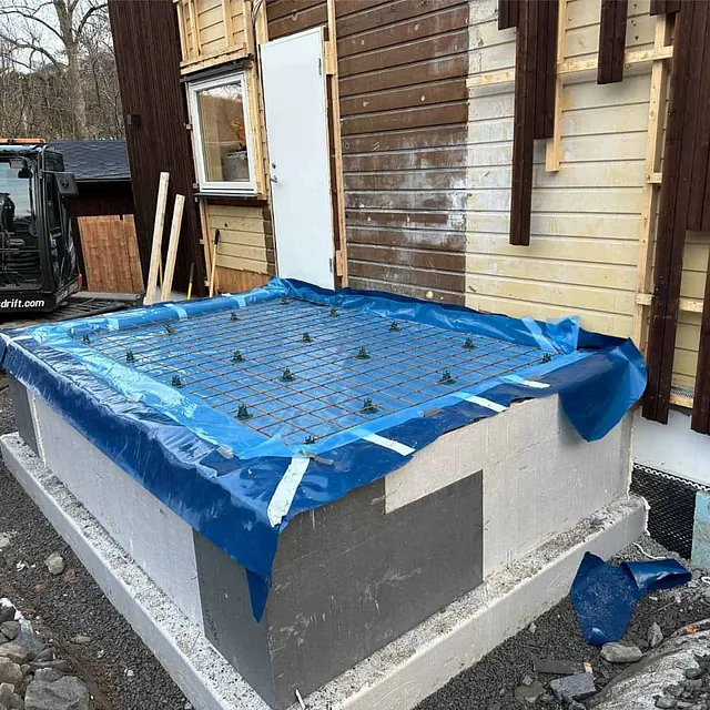 Armeringsnett og fuktsperre klargjort på isolert fundament før støping av betongplate.