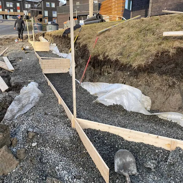 Forskalte seksjoner fylles med pukk og fiberduk som grunnlag for ny støttemur.