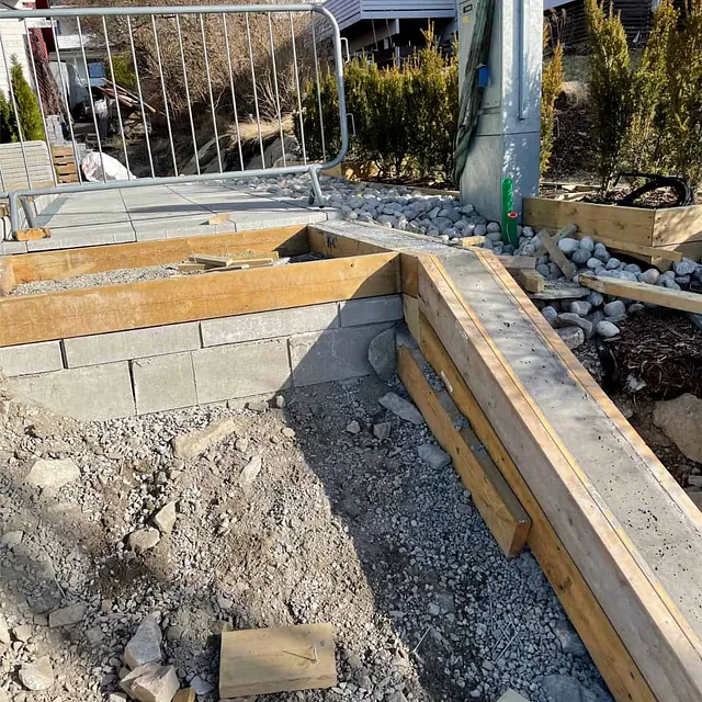 Forskalte betongvanger og platå under bygging som del av nytt trappeanlegg ved bolig.