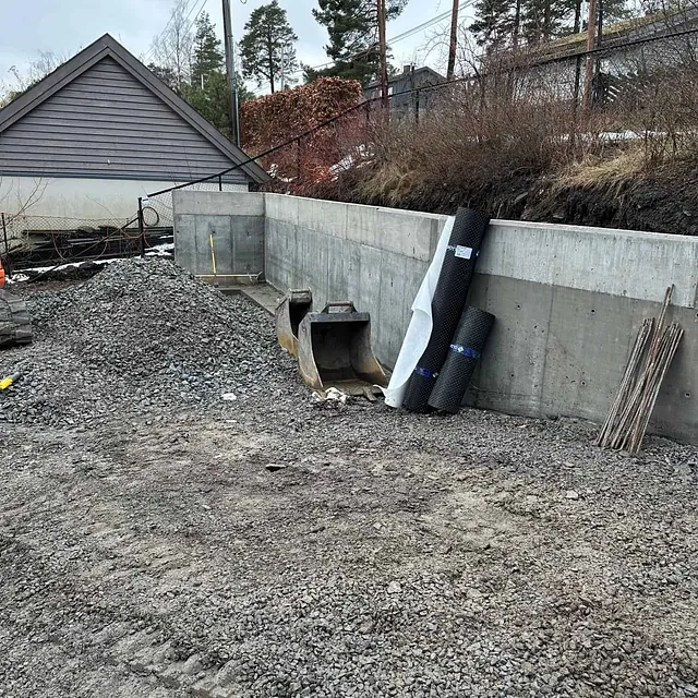 Støttemurer og gruslagt område danner grunnlag for videre terrengarbeid og utforming.