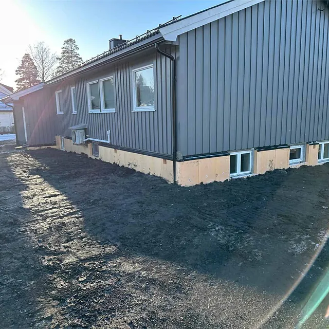 Tilbakefylt terreng rundt boligen etter dreneringsarbeid og montering av isolasjonsplater.