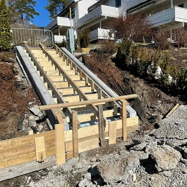 Betongtrapp under bygging med forskaling og armering, klargjort for støpearbeid utendørs.
