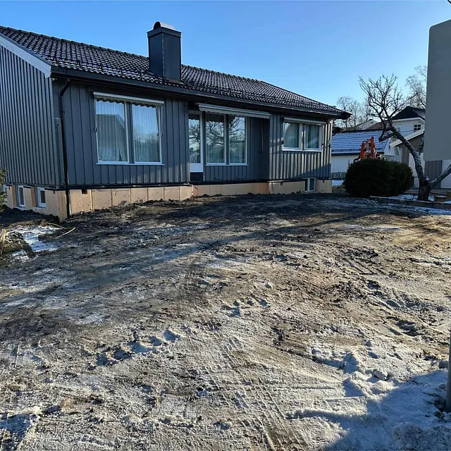 Ferdigstilt terreng rundt boligen etter dreneringsarbeid og tilbakefylling av masser.