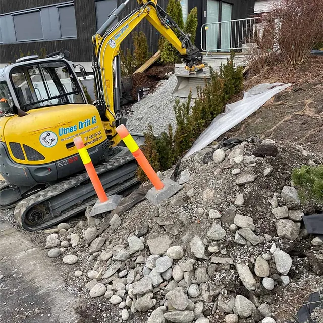 Grunnarbeider med gravemaskin ved framtidig trappeanlegg og terrengtilpasning ved bolig.