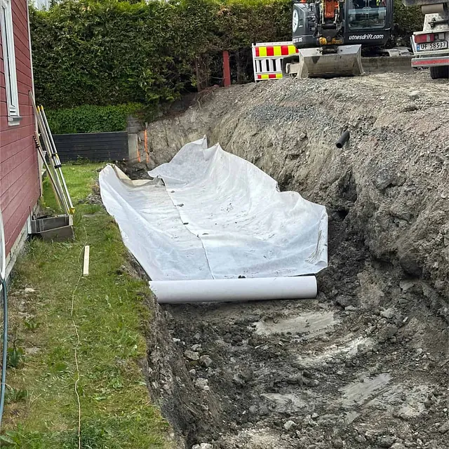 Fiberduk lagt i utgravd grøft som forberedelse til drenering og masseskifte.