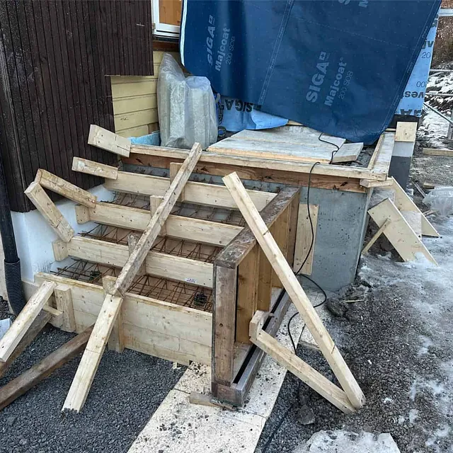 Forskalet betongtrapp med innlagt armering klargjort for støping ved inngangspartiet.
