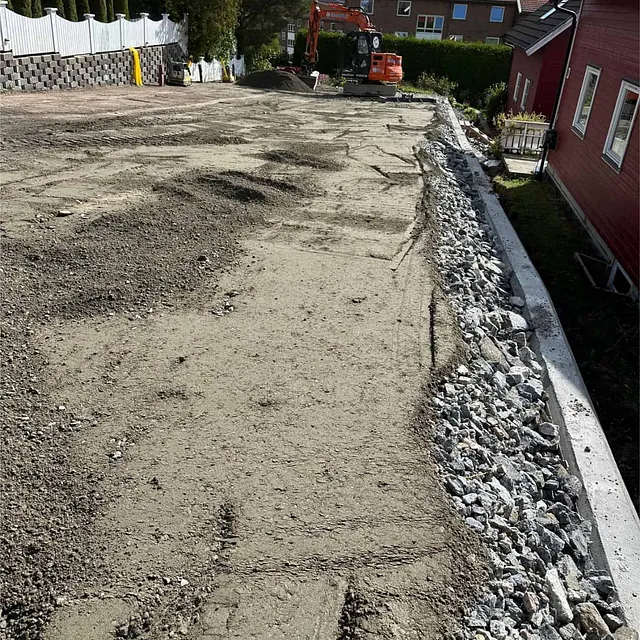 Oppbygget parkeringsområde med komprimerte masser og kantmur før asfaltering.