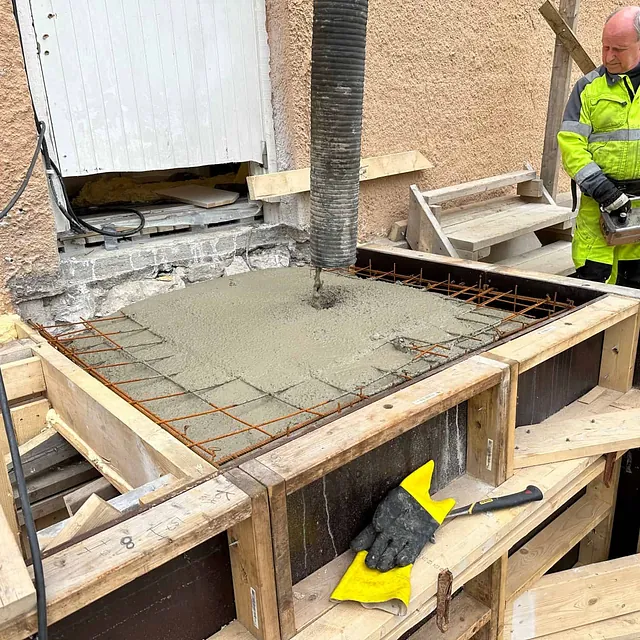 Betong støpes i forskaling med armering ved inngangsparti, som del av trappebygging.