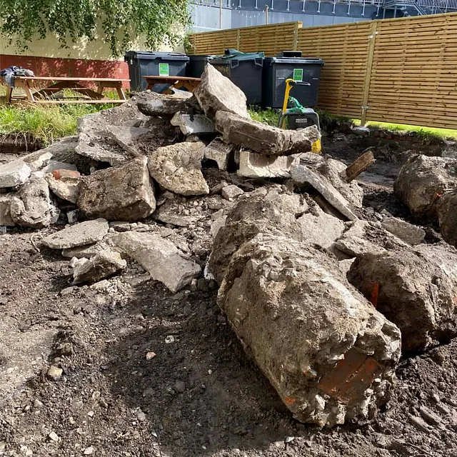 Oppbrutt betong og steinmasser samlet etter rivningsarbeid i forbindelse med oppgradering av uteområdet.