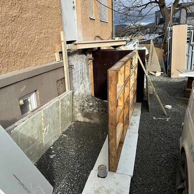 Forskaling montert ved husvegg for støping av betongkonstruksjon ved inngangsparti.