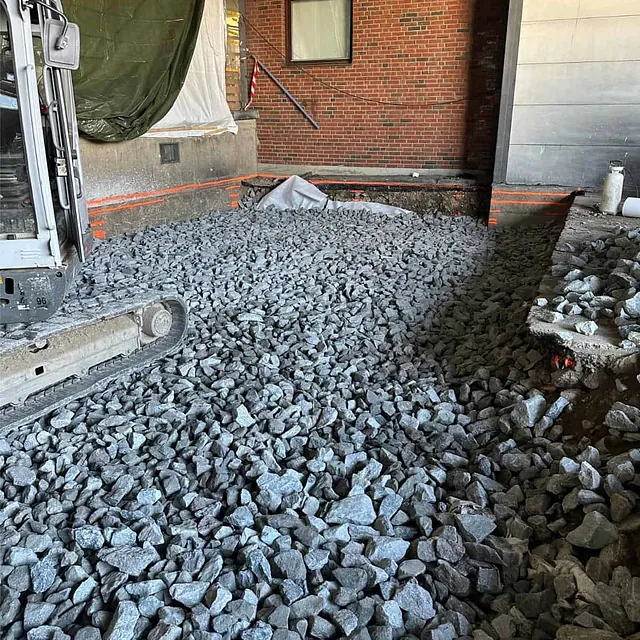 Pukk legges ut og avrettes som bærelag før etablering av ny armert betongplate.