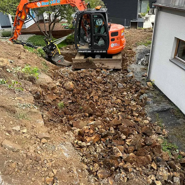 Utgraving og fjerning av sprengt berg gjennomføres for å klargjøre nytt uteområde.