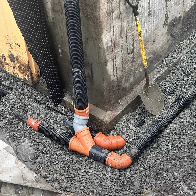 Drensrør koblet til nedløp ved fundament for trygg bortledning av overvann.