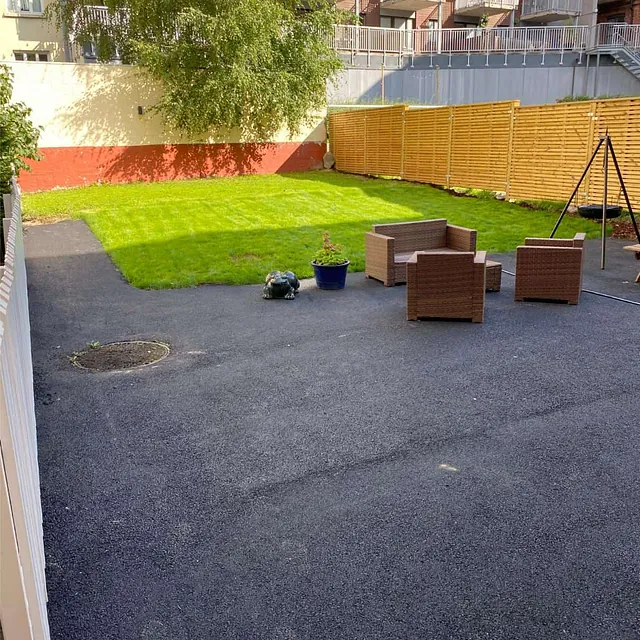 Ferdig opparbeidet uteområde med ny asfalt, plen og sittegruppe i felles bakgård.