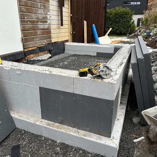 Fundament av forskalingsblokker fylt med pukk under oppføring av nytt tilbygg.