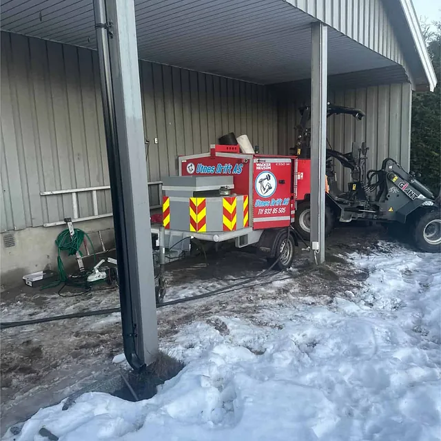 Utstyr og maskiner klargjort under carport i forbindelse med pågående dreneringsarbeid.