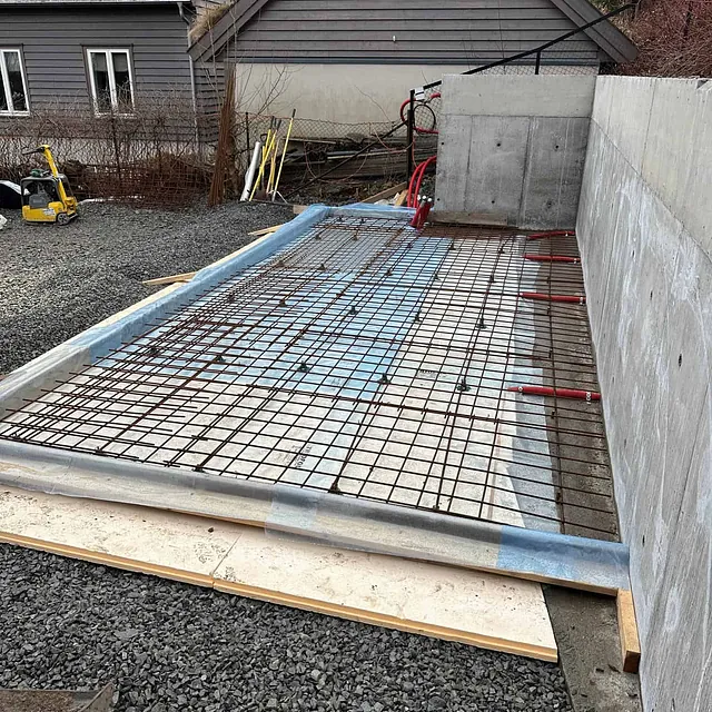 Armeringsnett og isolasjon klargjøres for støping av betongdekke ved støttemur.