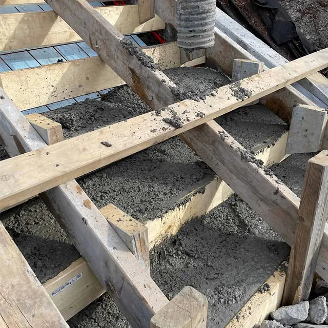 Betong pumpes og fordeles i trappeforskaling under støpearbeid for ny adkomsttrapp.