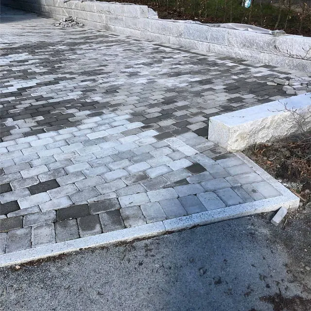 Ferdiglagt gårdsplass med belegningsstein og granittmur gir ryddig og varig uteområde.