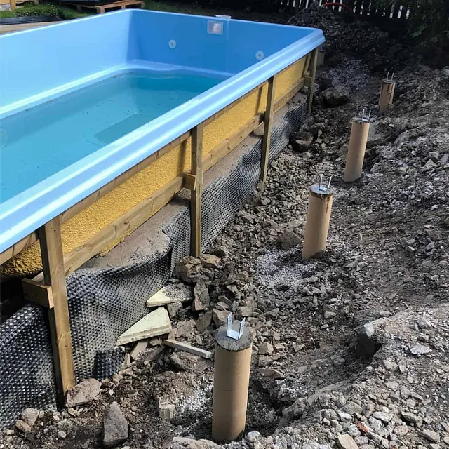 Støpte fundamentpunkter etablert rundt basseng som forberedelse til bygging av terrasse.